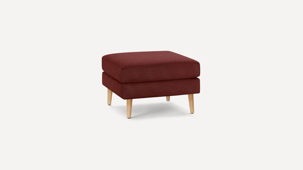 Square, upholstered ottoman in deep red fabric with light wooden tapered legs, placed on a white background.