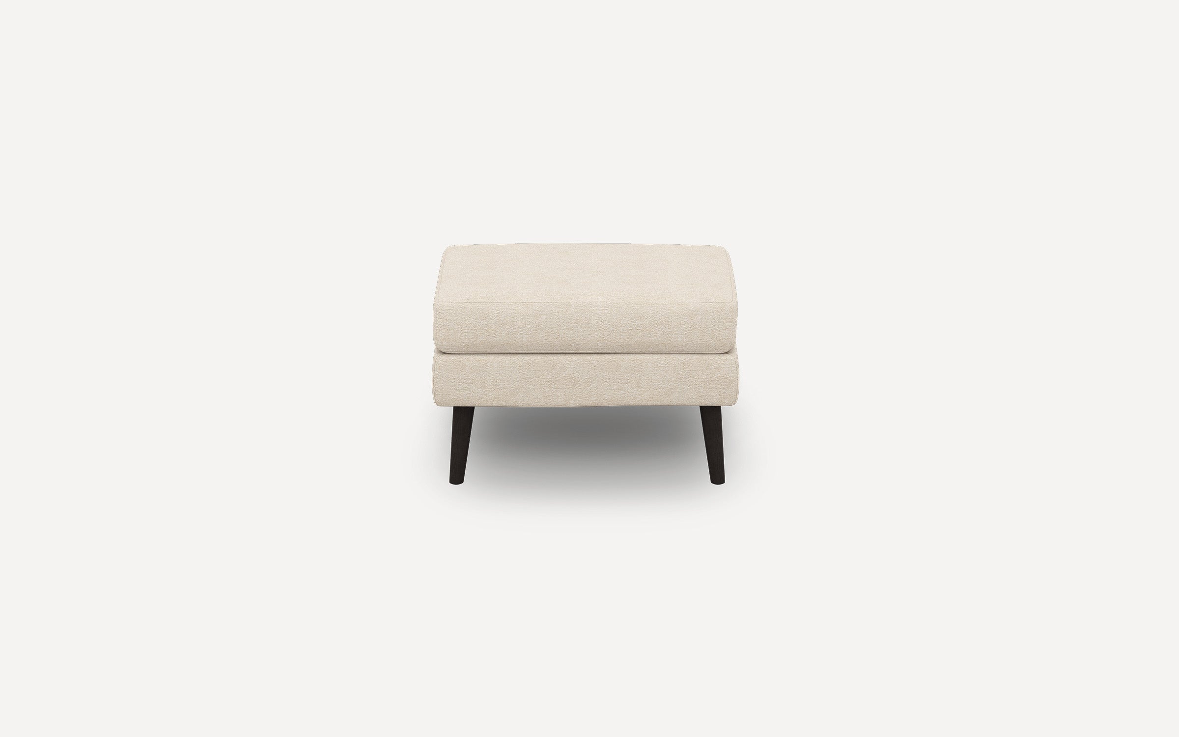 Beige rectangular ottoman with a padded cushion top and four dark wooden tapered legs, shown against a white background.