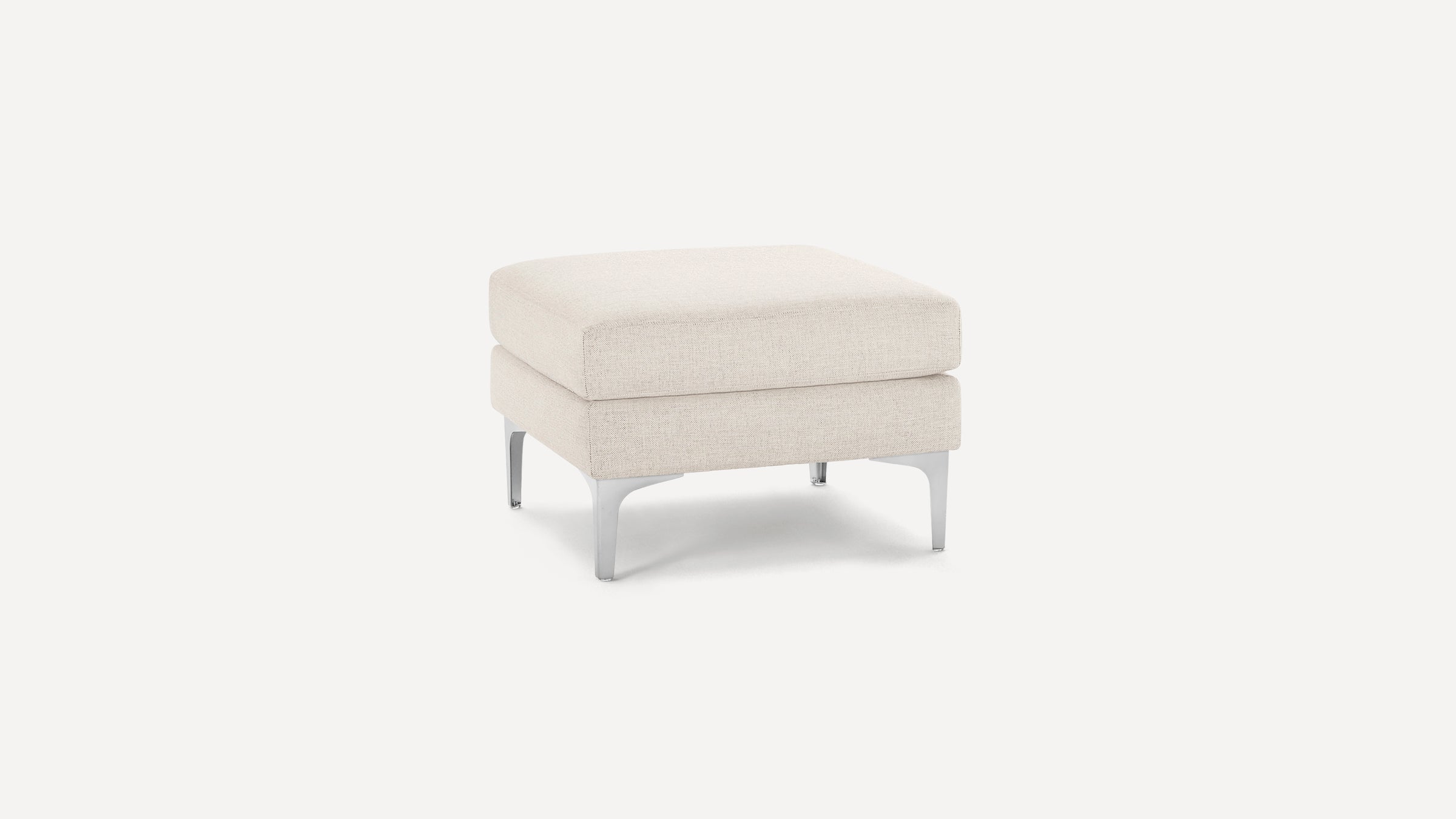 Square beige upholstered ottoman with thick cushion and metal legs, showcasing modern minimalist design.