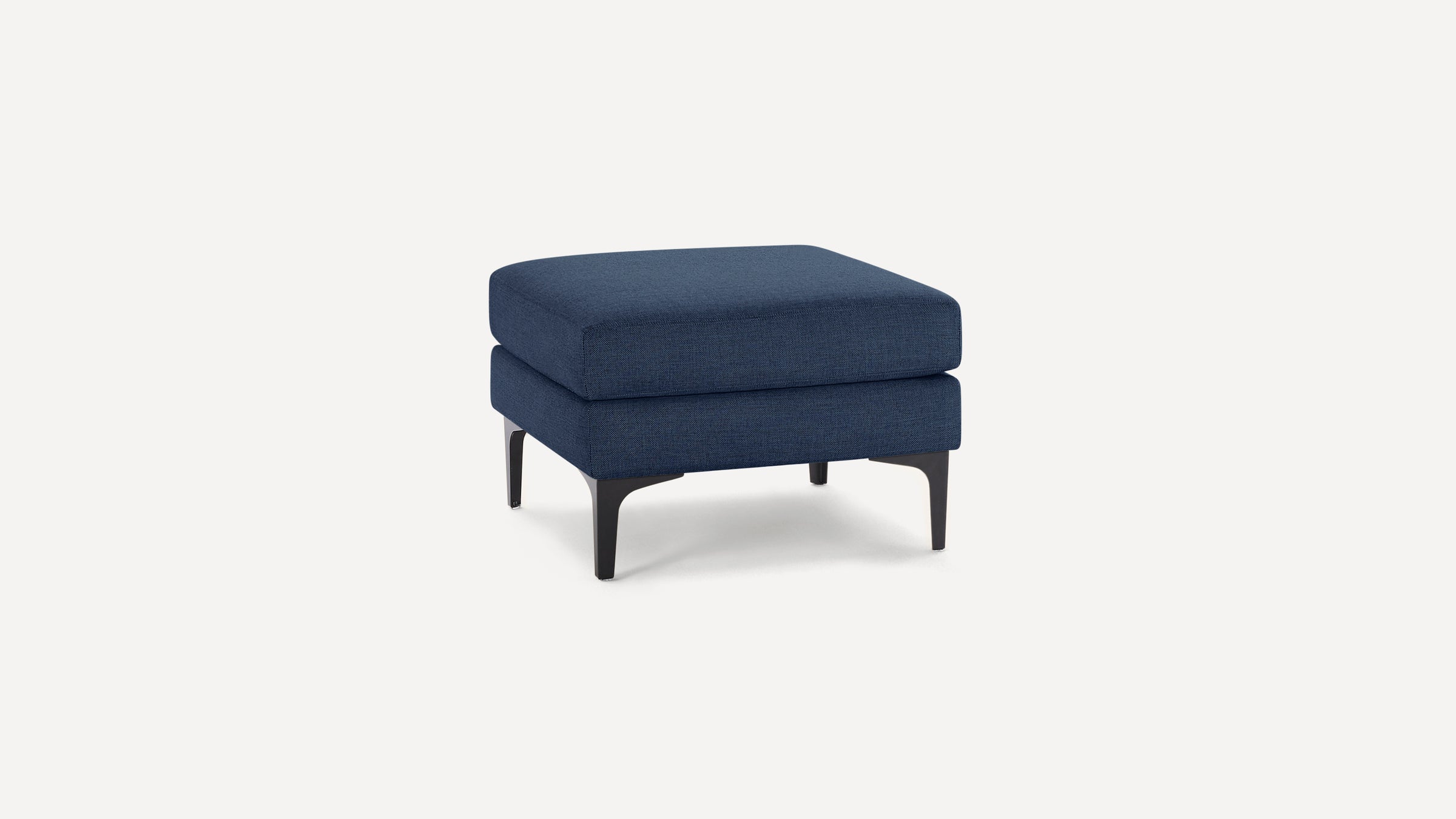 Square navy blue upholstered ottoman with black tapered legs on a white background.