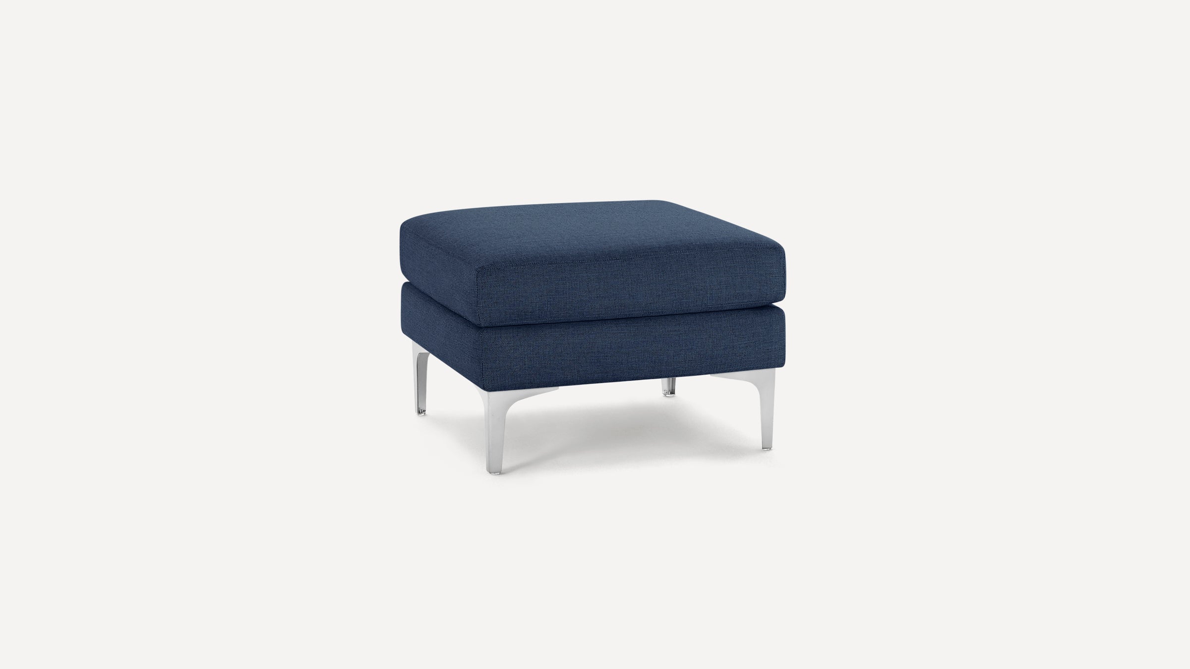 Small square ottoman with navy blue fabric upholstery and four silver metal legs on white background.