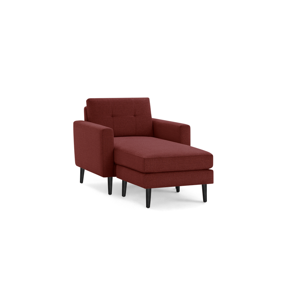 Modern chaise lounge chair in dark red fabric upholstery with tufted backrest, armrests, and black tapered wooden legs.
