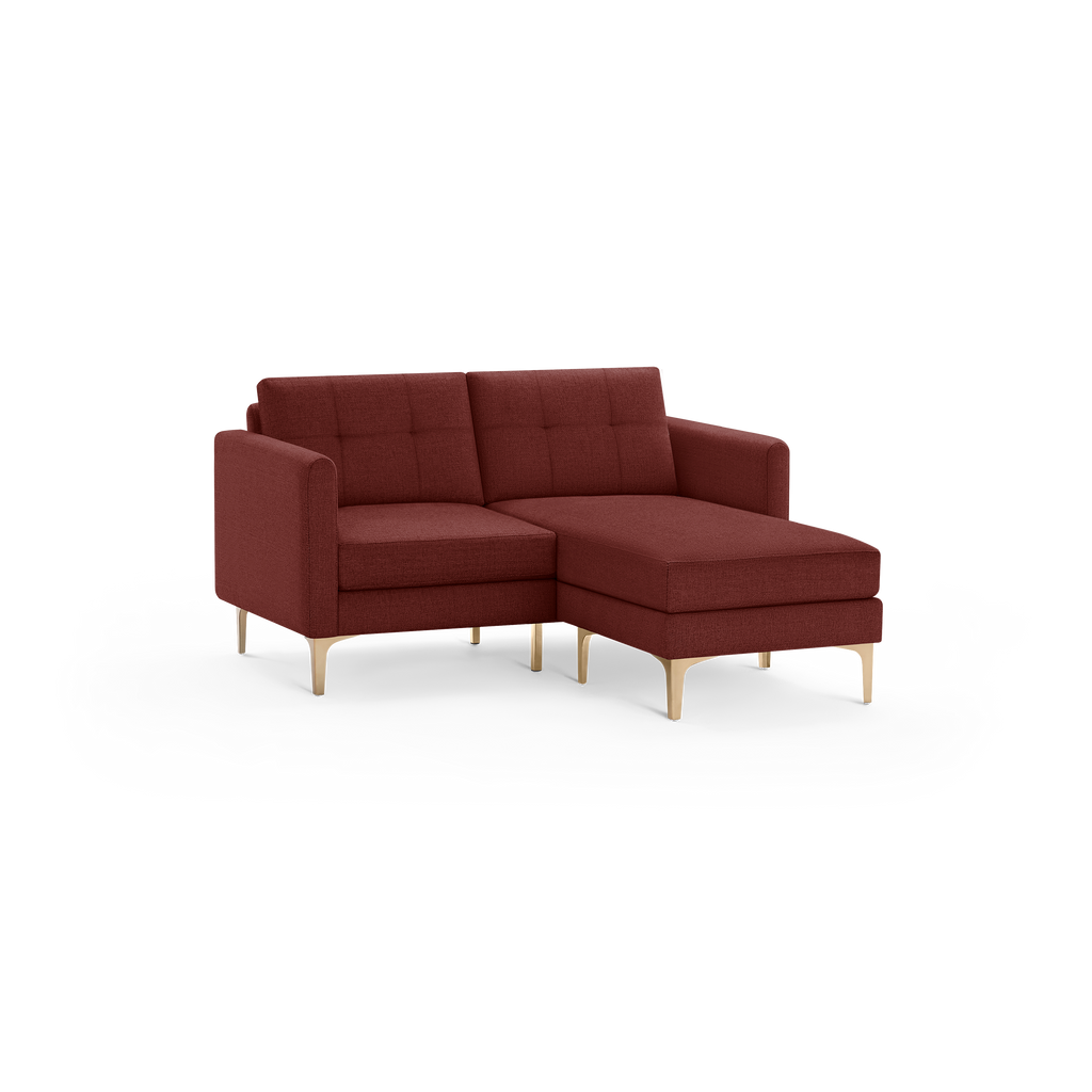 Modern sectional sofa in deep red fabric with tufted back cushions and light wood legs, featuring a chaise lounge on the right side.