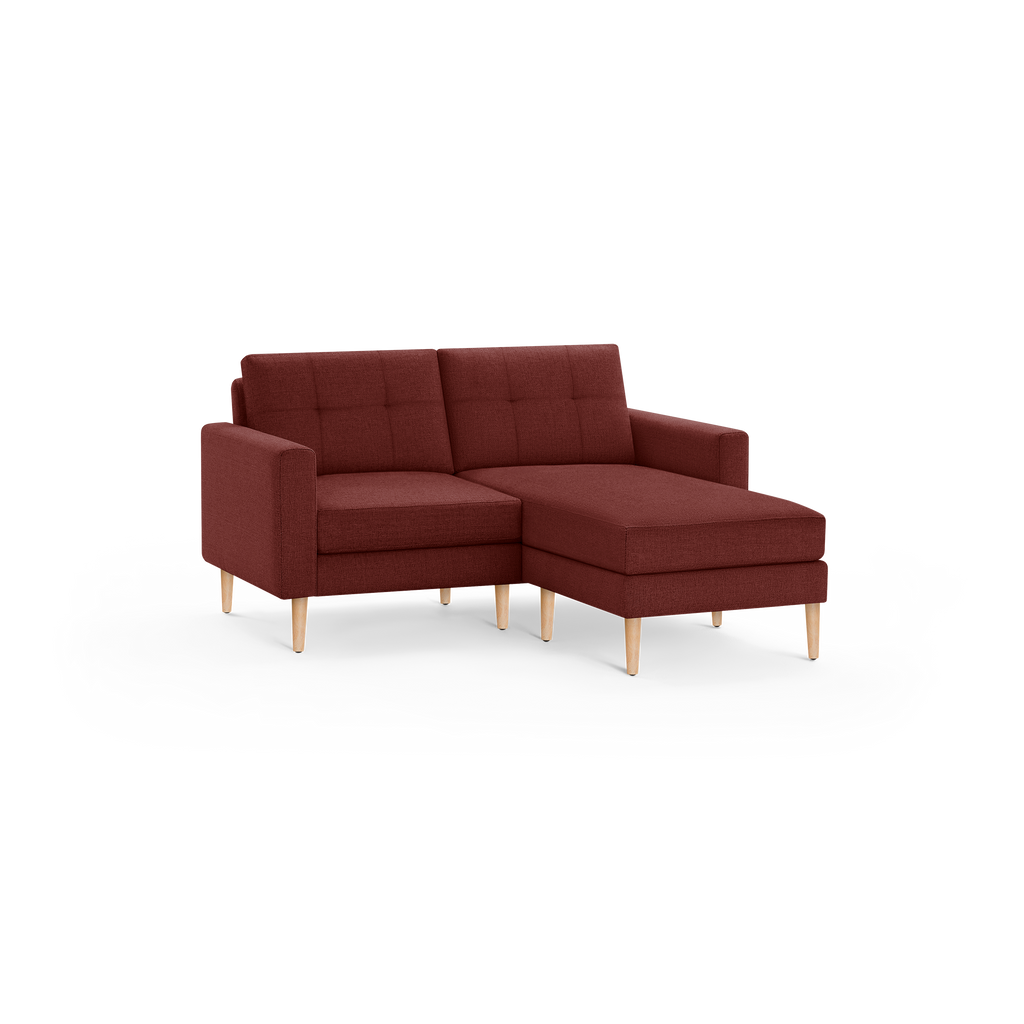 Modern sectional sofa with right chaise, upholstered in dark red fabric, featuring tufted back cushions and light wooden legs.
