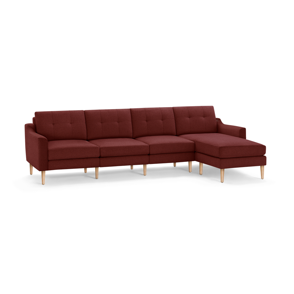 Modern sectional sofa with chaise in deep red fabric upholstery and light wooden legs, featuring tufted back cushions.