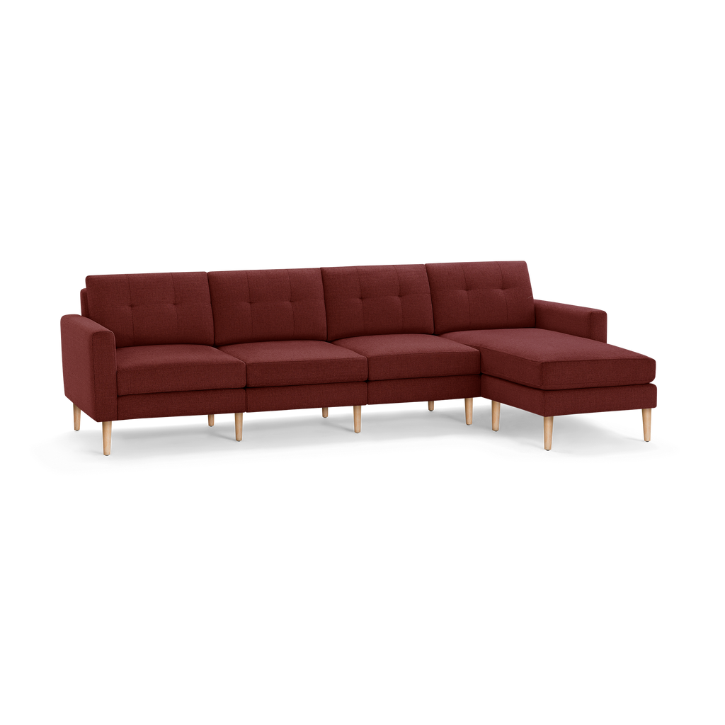 Modern L-shaped sectional sofa with deep red fabric upholstery, button-tufted back cushions, wooden legs, and a chaise on the right side.