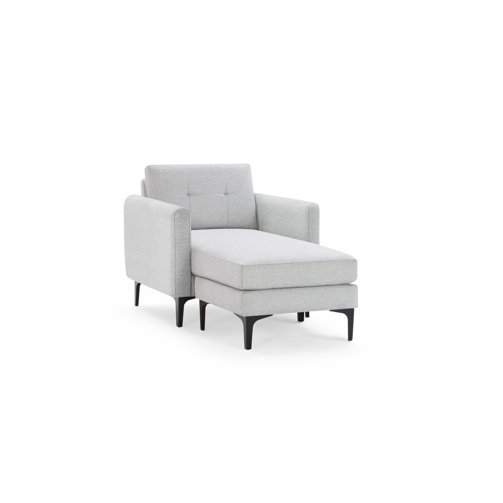 Light grey upholstered chaise lounge chair with tufted backrest and black slender legs, offering modern comfort and style.