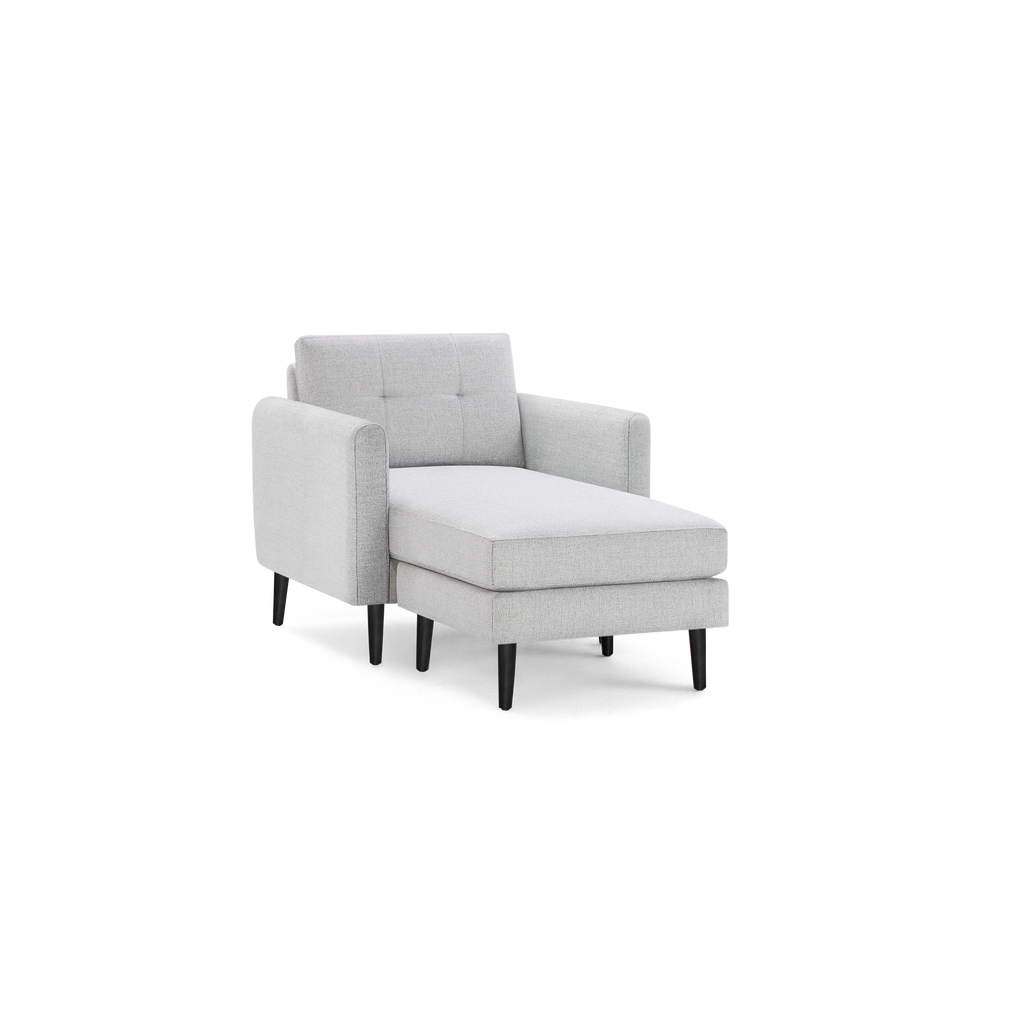 Light gray upholstered chaise lounge chair with tufted backrest, smooth seat cushion, armrests, and tapered dark wooden legs.
