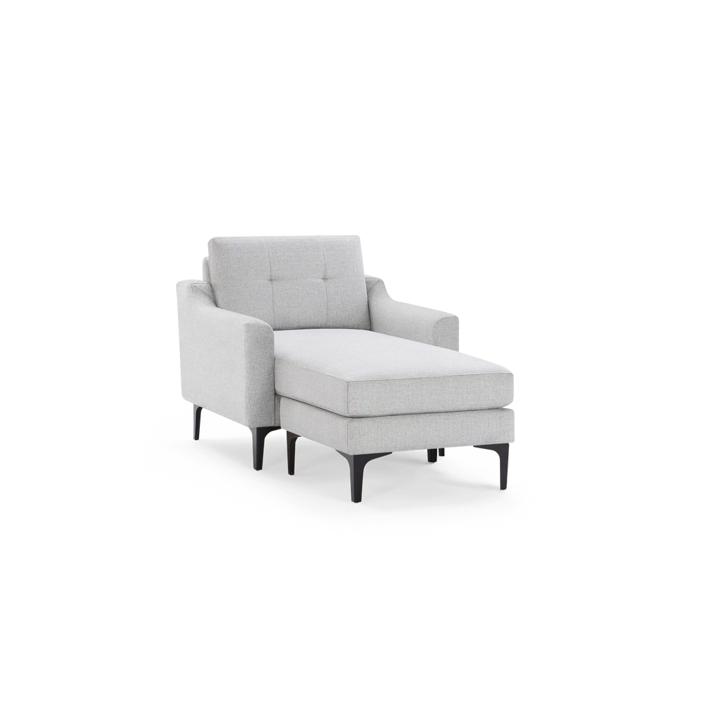 Light gray upholstered chaise lounge chair with tufted backrest, padded armrests, and black metal legs.