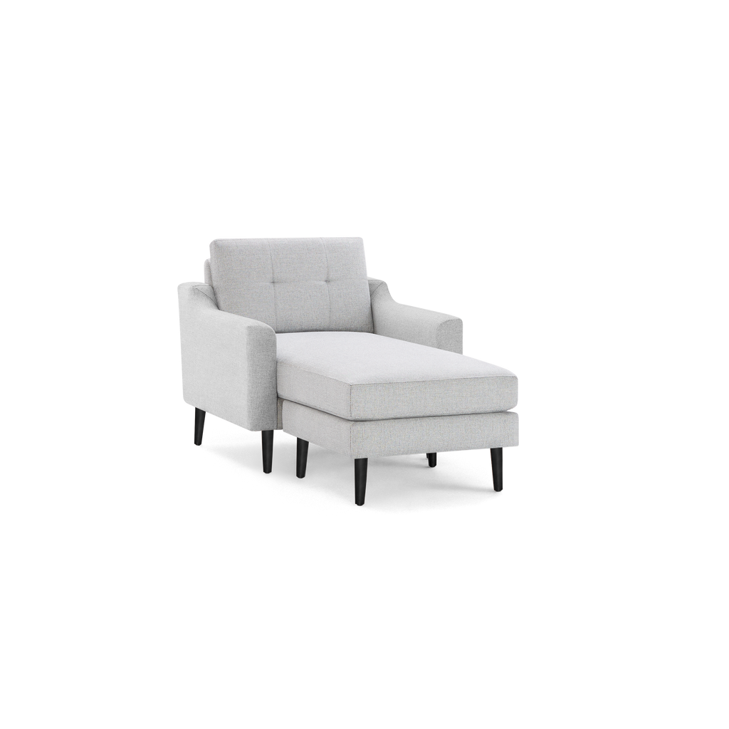Light gray upholstered chaise lounge chair with tufted backrest, armrests, and black tapered wooden legs.