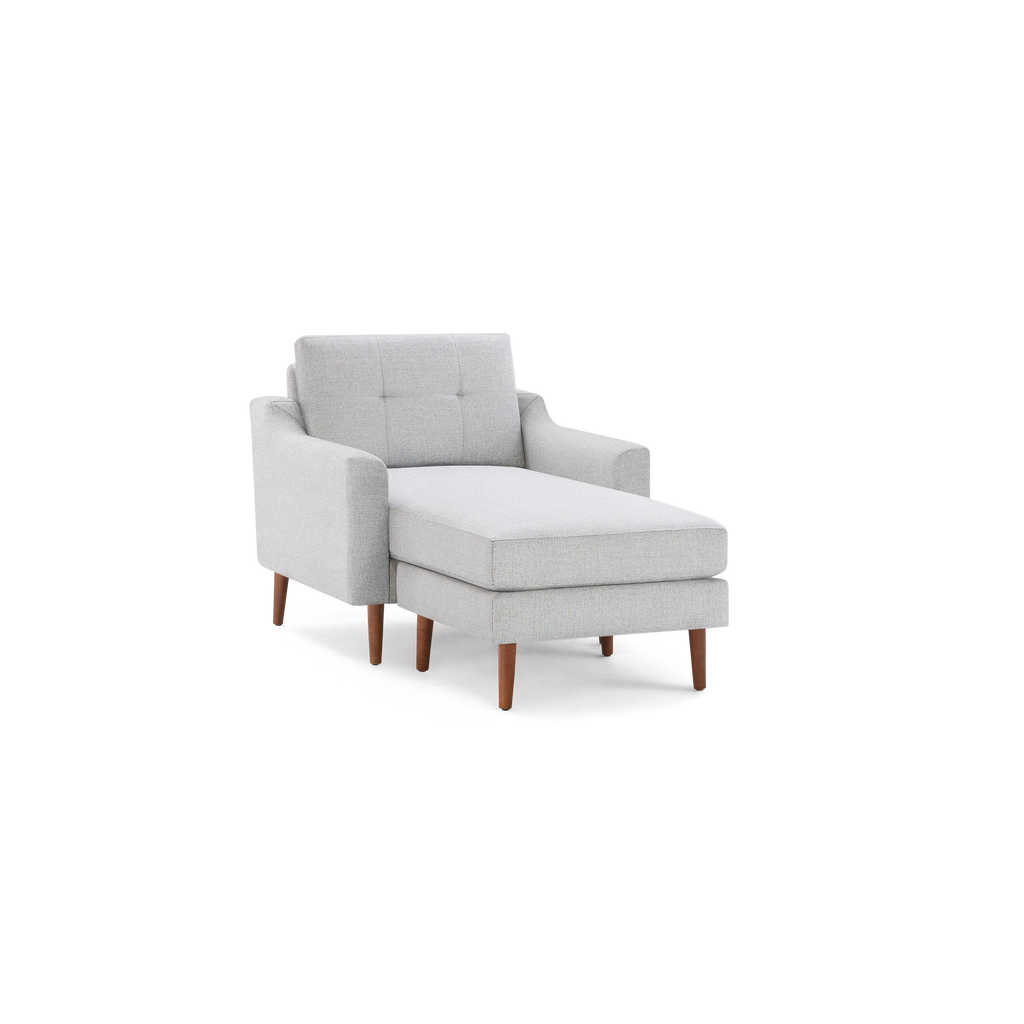 Light gray upholstered chaise lounge with tufted backrest, curved armrests, and tapered wooden legs in a mid-century modern style.
