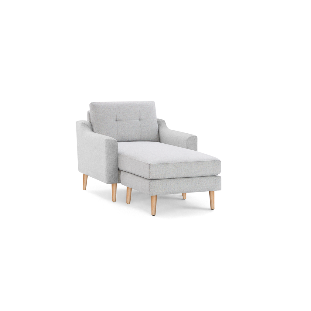 Light gray upholstered chaise lounge chair with tufted backrest, armrests, and natural wooden legs.