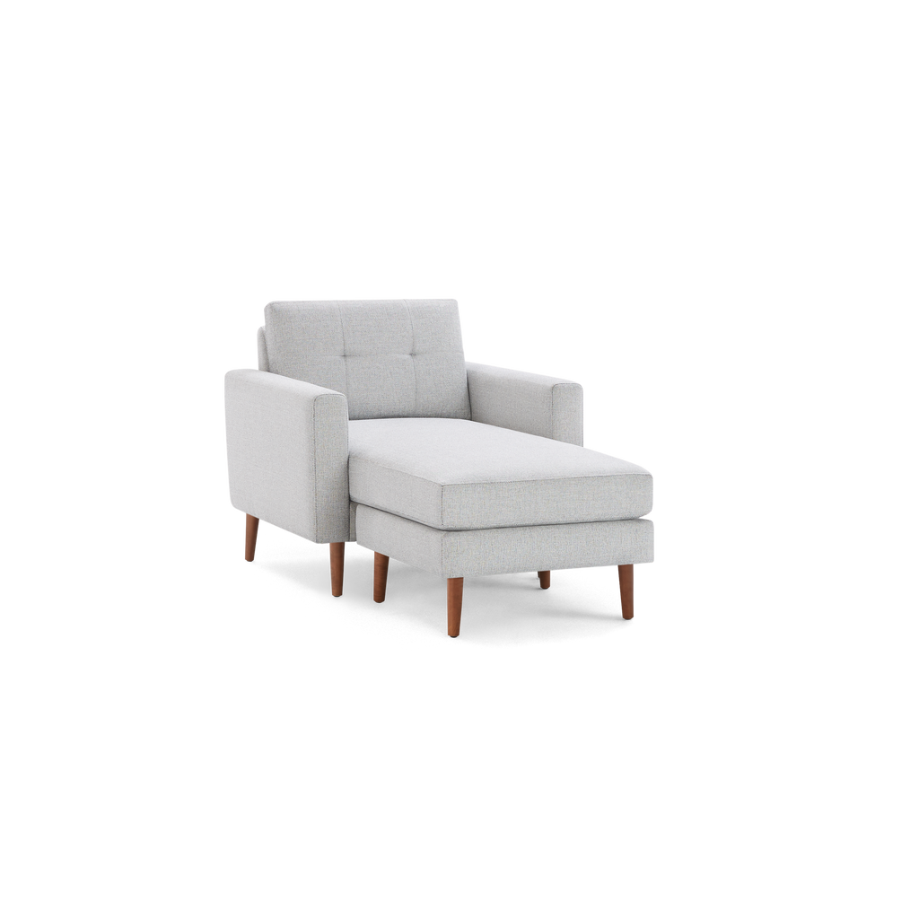 Light grey upholstered chaise lounge chair with wooden legs and tufted backrest, modern and minimalist design.