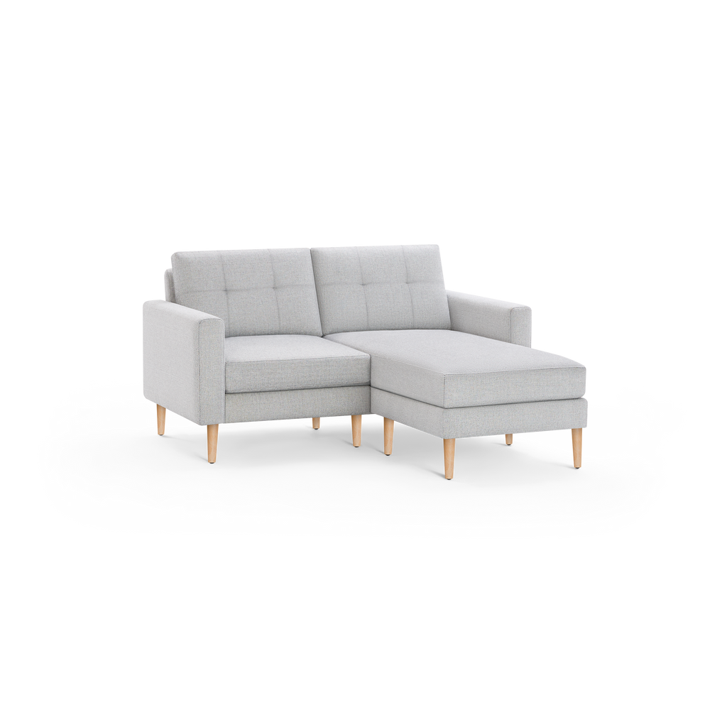 Light gray tufted fabric sectional sofa with wooden legs, featuring a right-side chaise lounge.