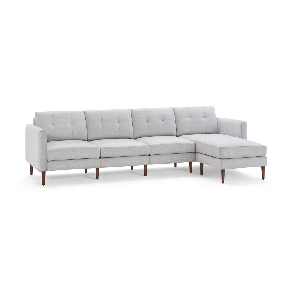 Light gray fabric sectional sofa with tufted back cushions, wooden legs, and a right-side chaise lounge.