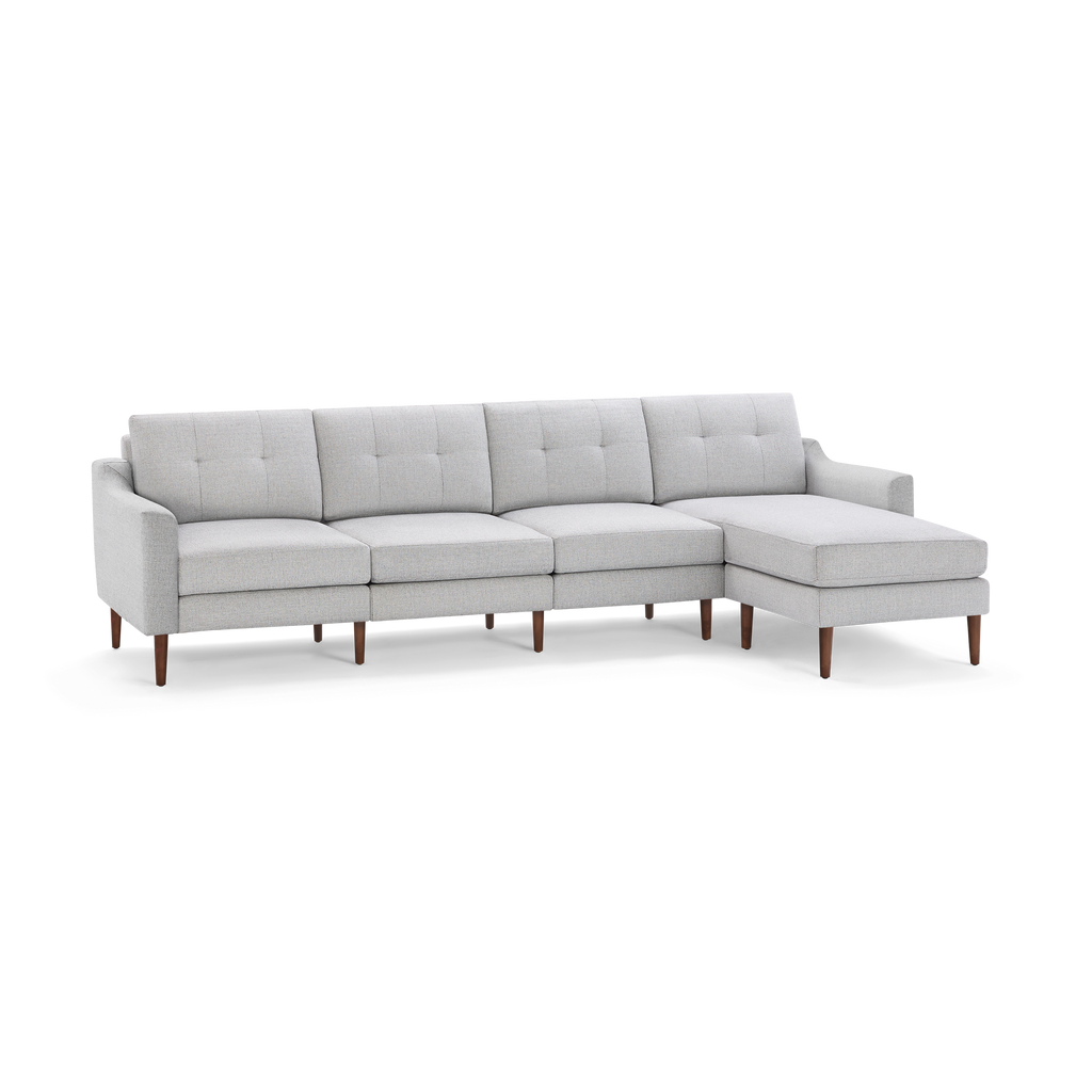 Light gray fabric sectional sofa with tufted back cushions, wooden legs, and right-side chaise lounge.