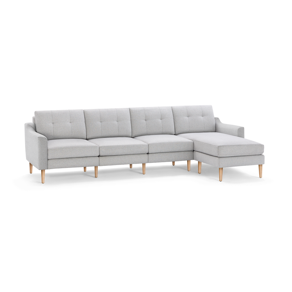 Light gray fabric sectional sofa with tufted back cushions, wooden tapered legs, and an attached right-side chaise lounge.