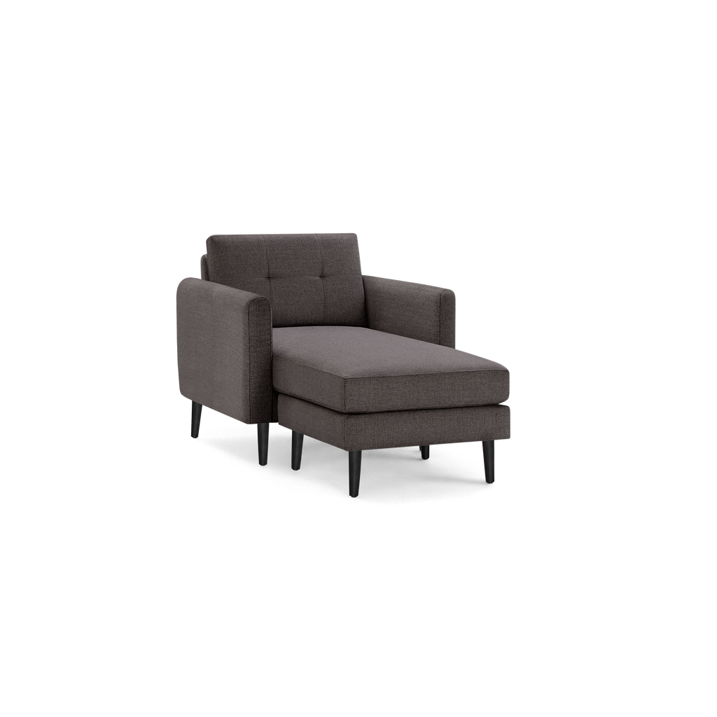 Gray fabric upholstered armchair with a chaise lounge extension, tufted backrest, and black wooden legs, shown against a black background.