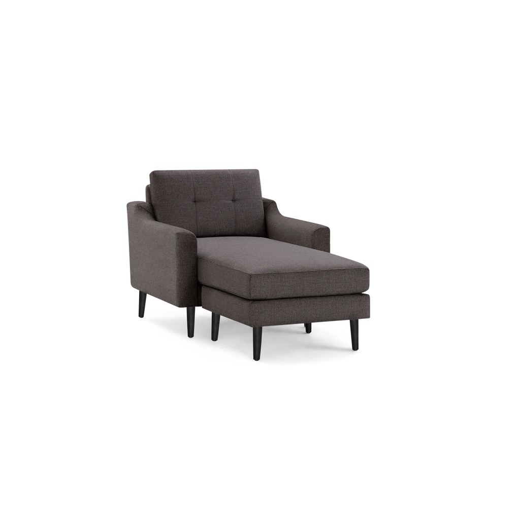Modern dark gray fabric chaise lounge chair with tufted backrest, cushioned seat, armrests, and black tapered wooden legs.