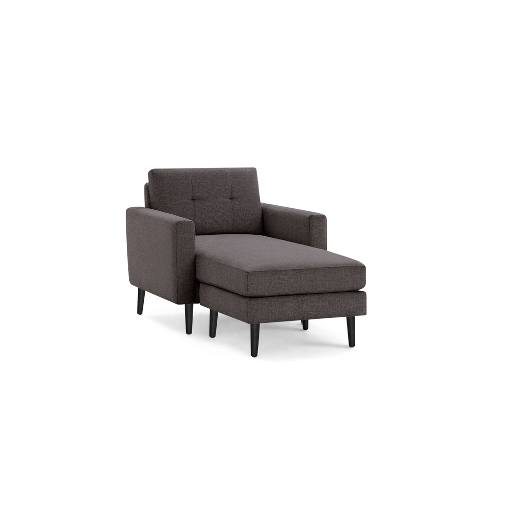 Modern dark gray upholstered chaise lounge chair with tufted backrest, rectangular armrests, and black slender wooden legs.