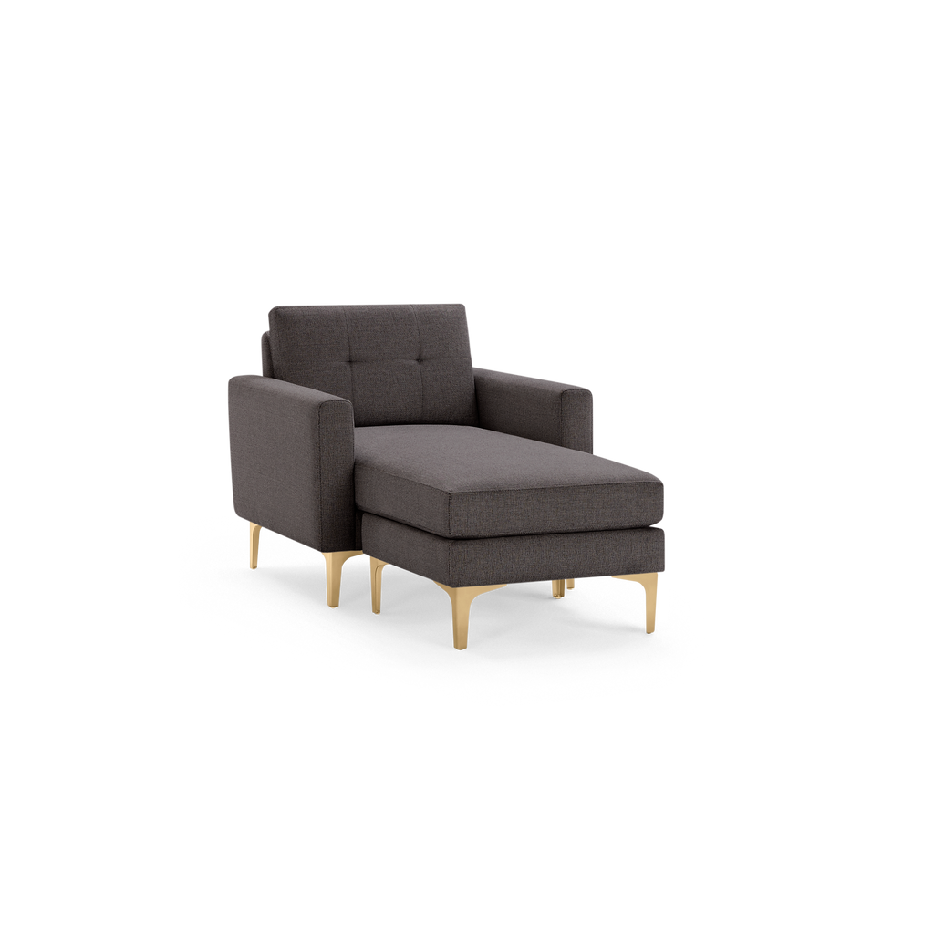 Modern dark gray chaise lounge chair with tufted backrest, straight armrests, and gold metal legs on black background.