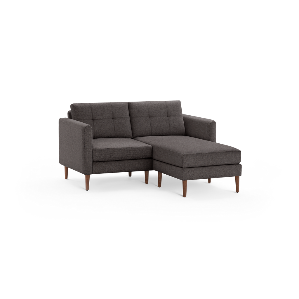 Dark gray fabric sectional loveseat with tufted back cushions and wooden tapered legs, featuring a chaise lounge on the right side.