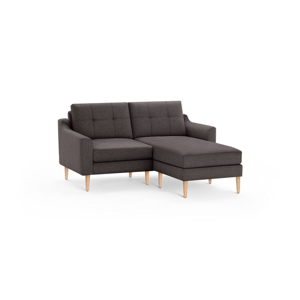Dark gray fabric sectional sofa with tufted back cushions and light wooden legs, featuring a right-side chaise lounge.