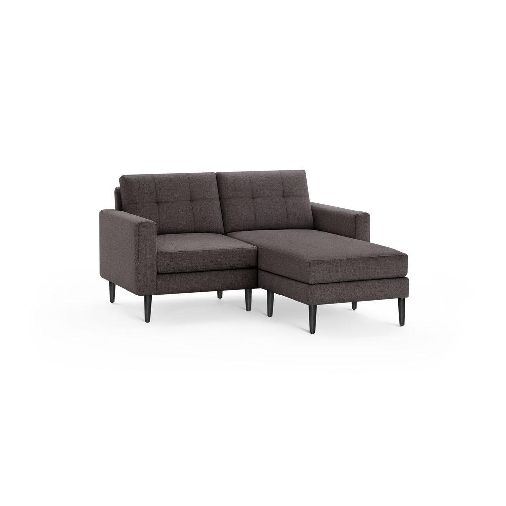 Modern dark gray fabric sectional sofa with tufted back cushions, right chaise, and slender black legs.