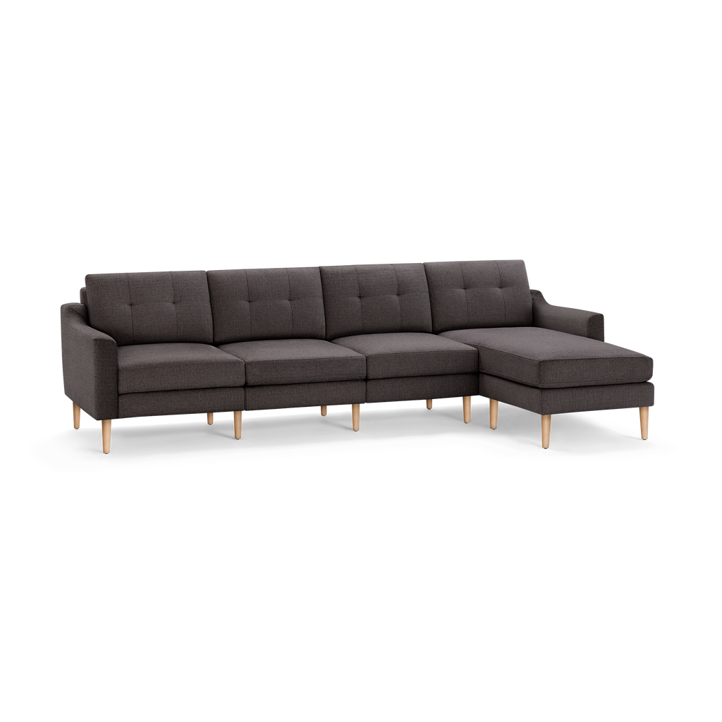 Modern dark gray fabric sectional sofa with tufted cushions and light wooden legs, featuring a chaise lounge on the right side.