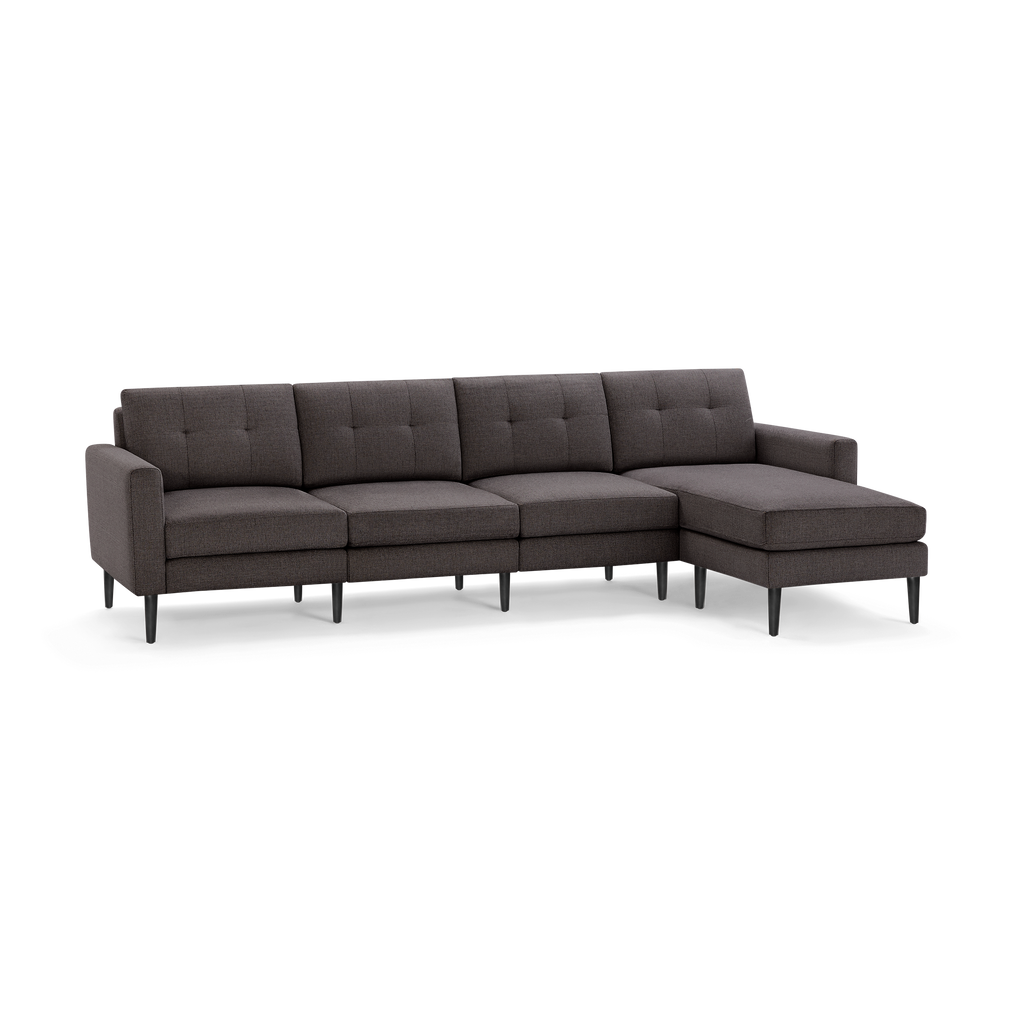 Dark gray fabric sectional sofa with tufted back cushions, straight armrests, and black tapered legs, featuring a chaise lounge on the right side.