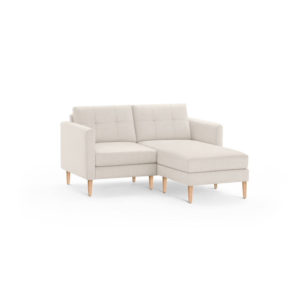 Beige modern sectional sofa with tufted back cushions, right chaise, fabric upholstery, and natural wooden tapered legs.