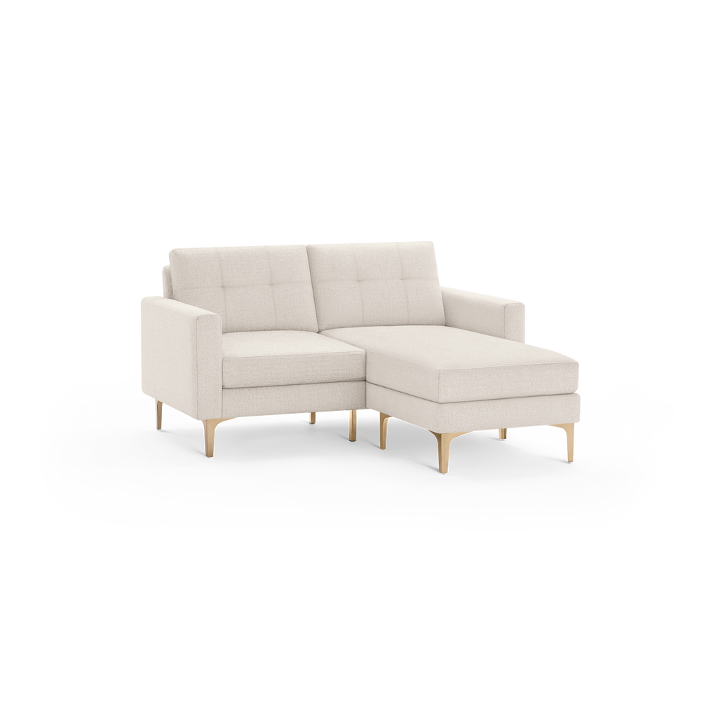 Beige upholstered sectional sofa with tufted backrest, cushioned seating, straight arms, and light wood legs.