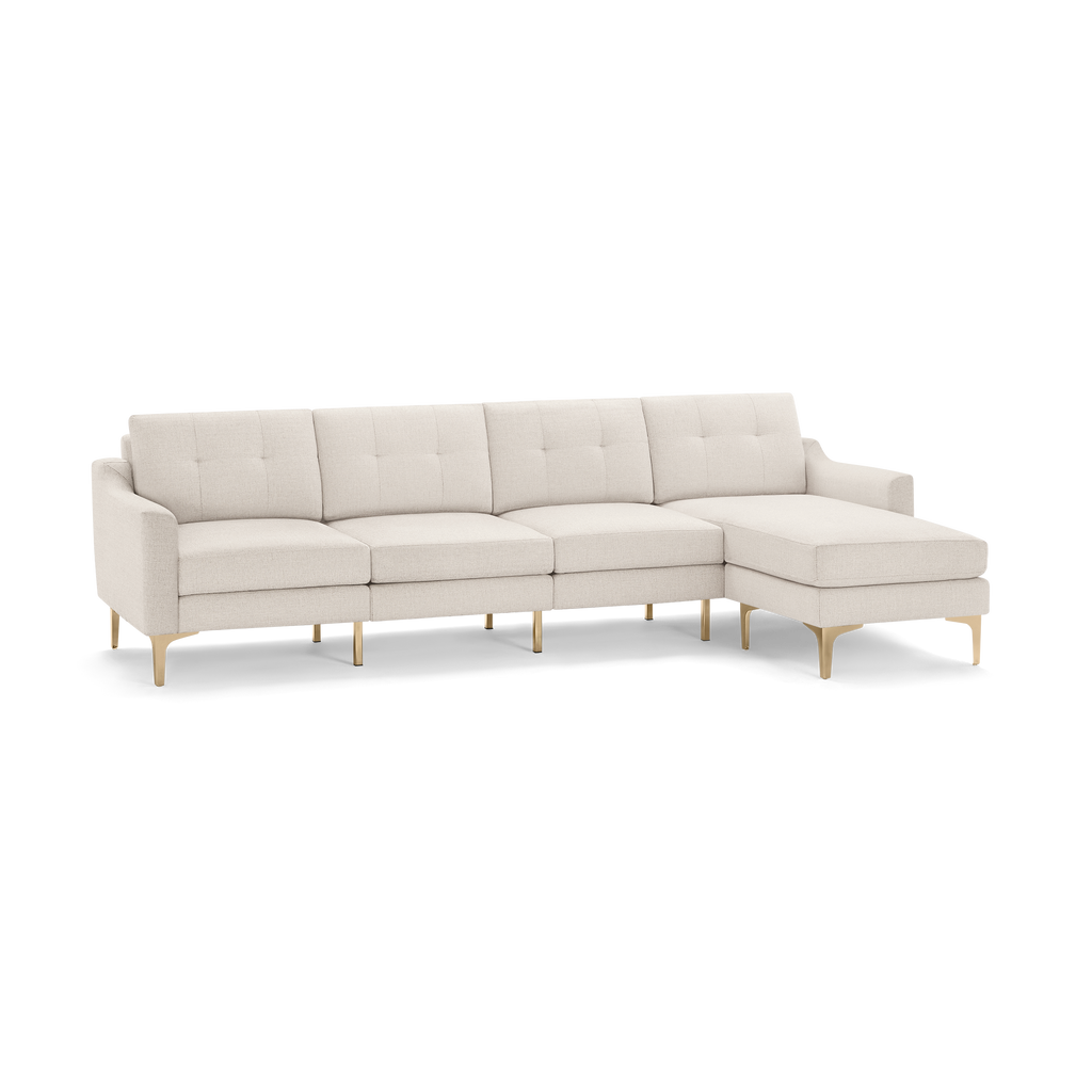 Beige fabric sectional sofa with tufted cushions, slim armrests, and gold metal legs, featuring chaise lounge on right side.