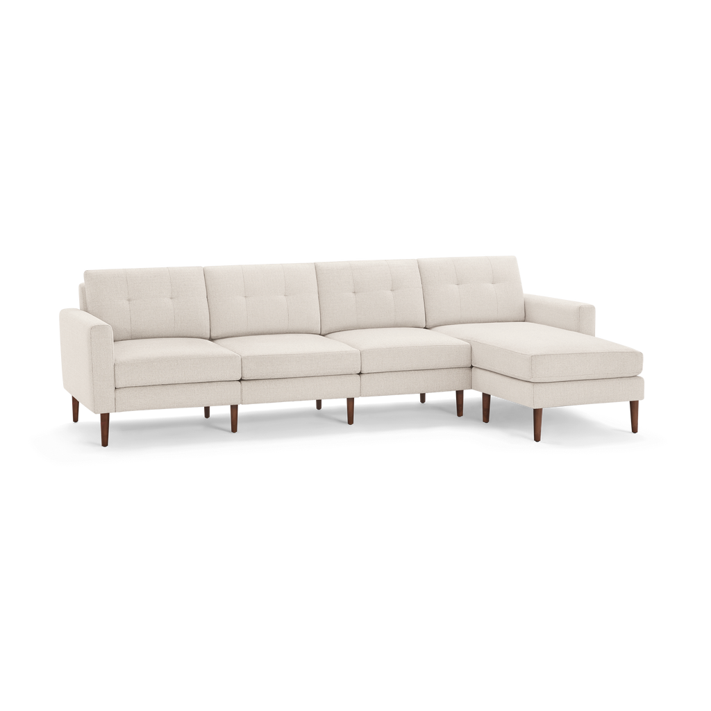 Beige modern sectional sofa with tufted cushions, wooden legs, and chaise lounge on the right side, providing spacious seating.
