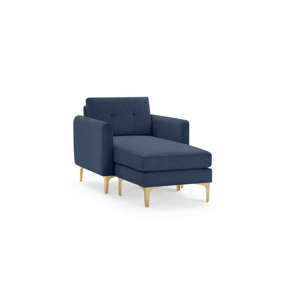 Blue upholstered chaise lounge chair with square arms, tufted backrest, and gold metal legs on black background.