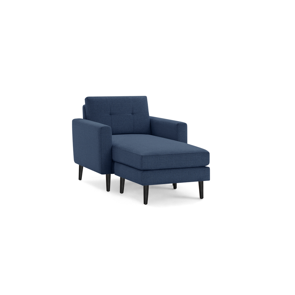 Blue upholstered chaise lounge chair with tufted backrest and wooden tapered legs on black background.