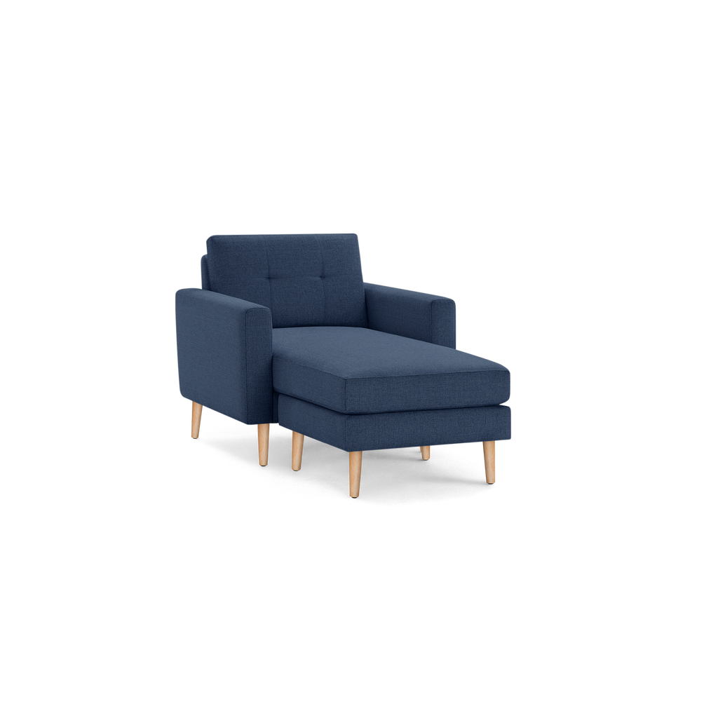 Modern navy blue upholstered chaise lounge chair with tufted backrest and light wooden tapered legs.
