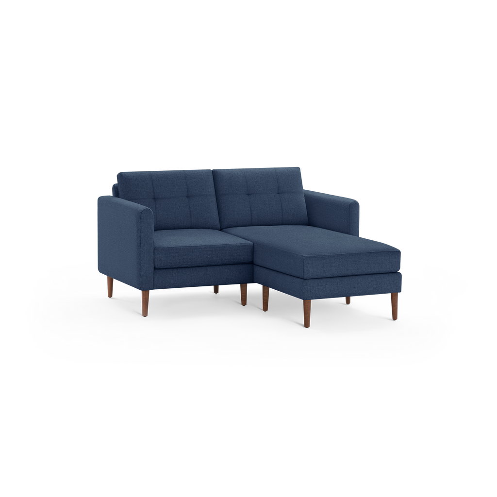 Modern navy blue fabric sectional sofa with tufted back cushions and wooden tapered legs, featuring a chaise lounge extension on the right.
