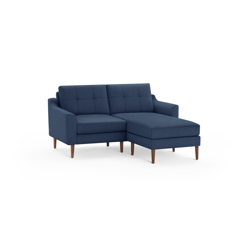 Modern navy blue fabric sectional sofa with tufted cushions and wooden legs, featuring a chaise lounge on the right side.