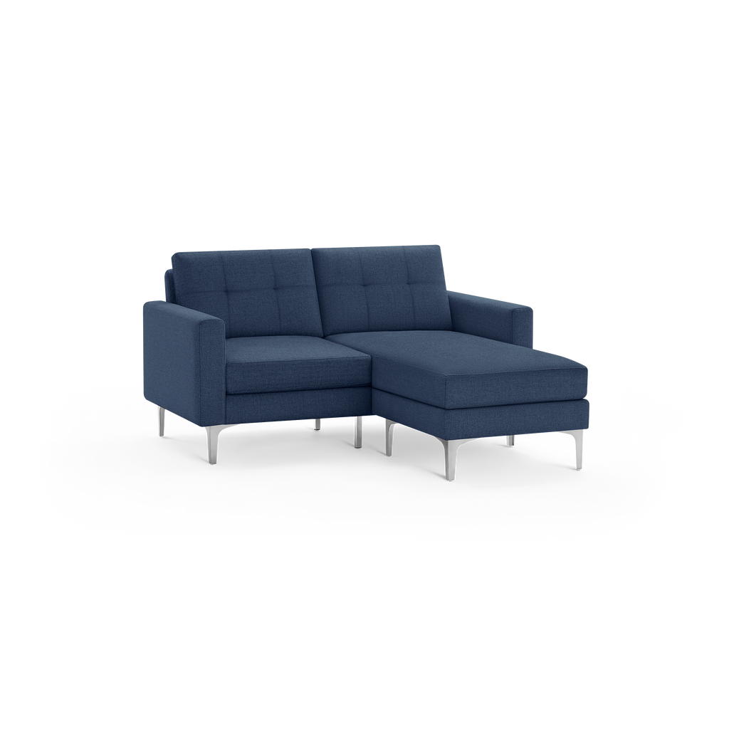 Modern dark blue fabric sectional sofa with tufted back cushions, silver metal legs, and chaise lounge on the right side.