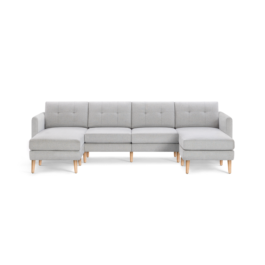 Light gray fabric sectional sofa with tufted back cushions, wooden legs, and chaise lounges on both ends, modern design.