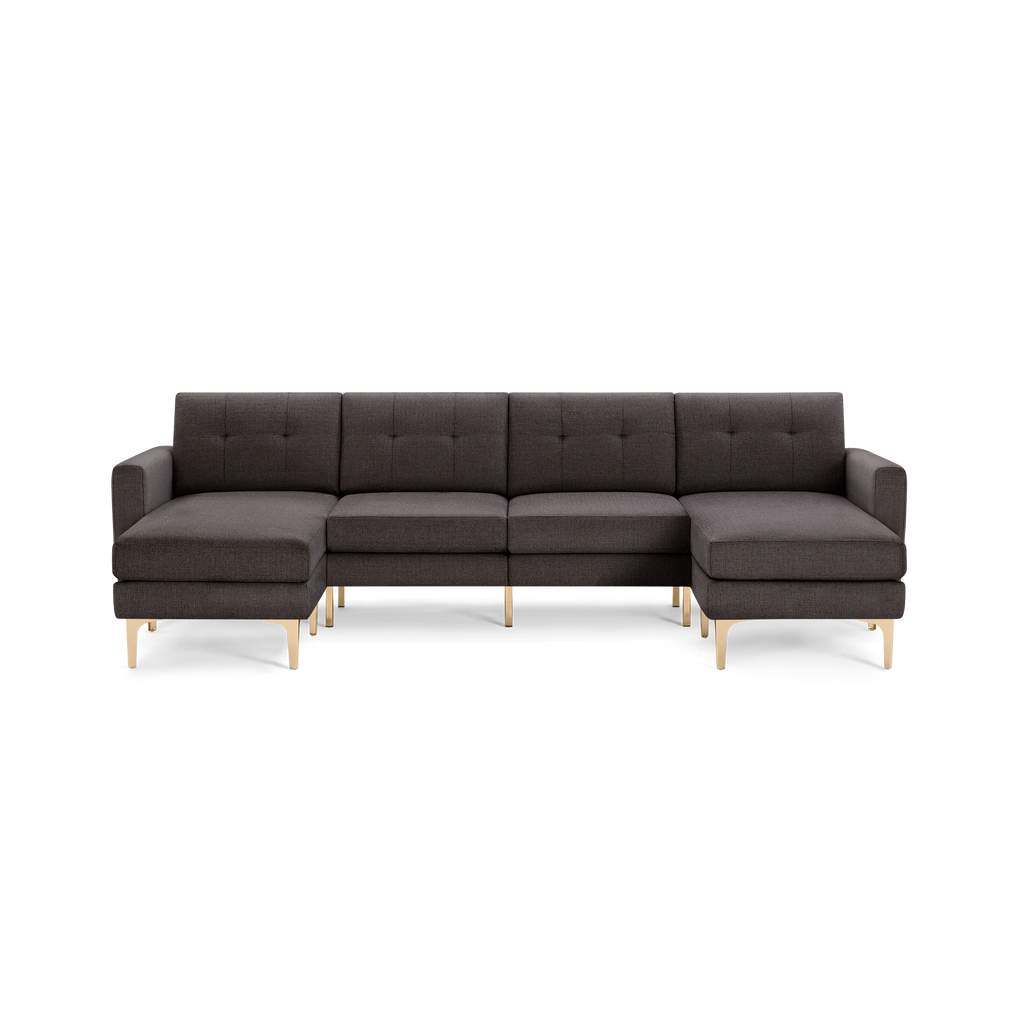 Dark gray modern sectional sofa with tufted back cushions, L-shaped design, and light wooden legs, isolated on black background.