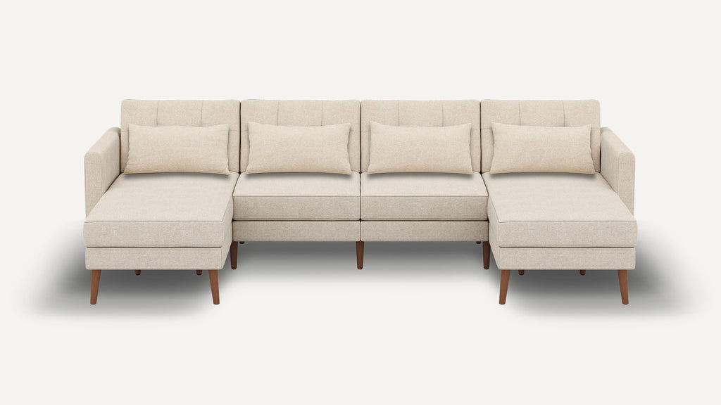 Beige sectional sofa with chaise lounges on both ends, four back cushions, wooden legs, and minimalist design.