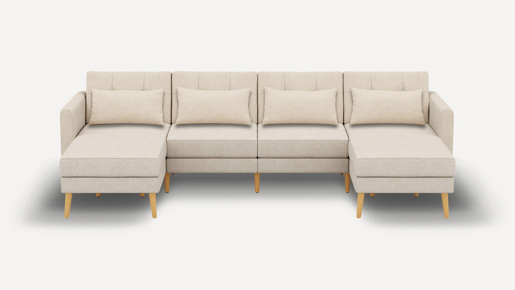 Beige modern sectional sofa with wooden legs, featuring a middle seating area and two chaise lounges on either end, each with a rectangular cushion.