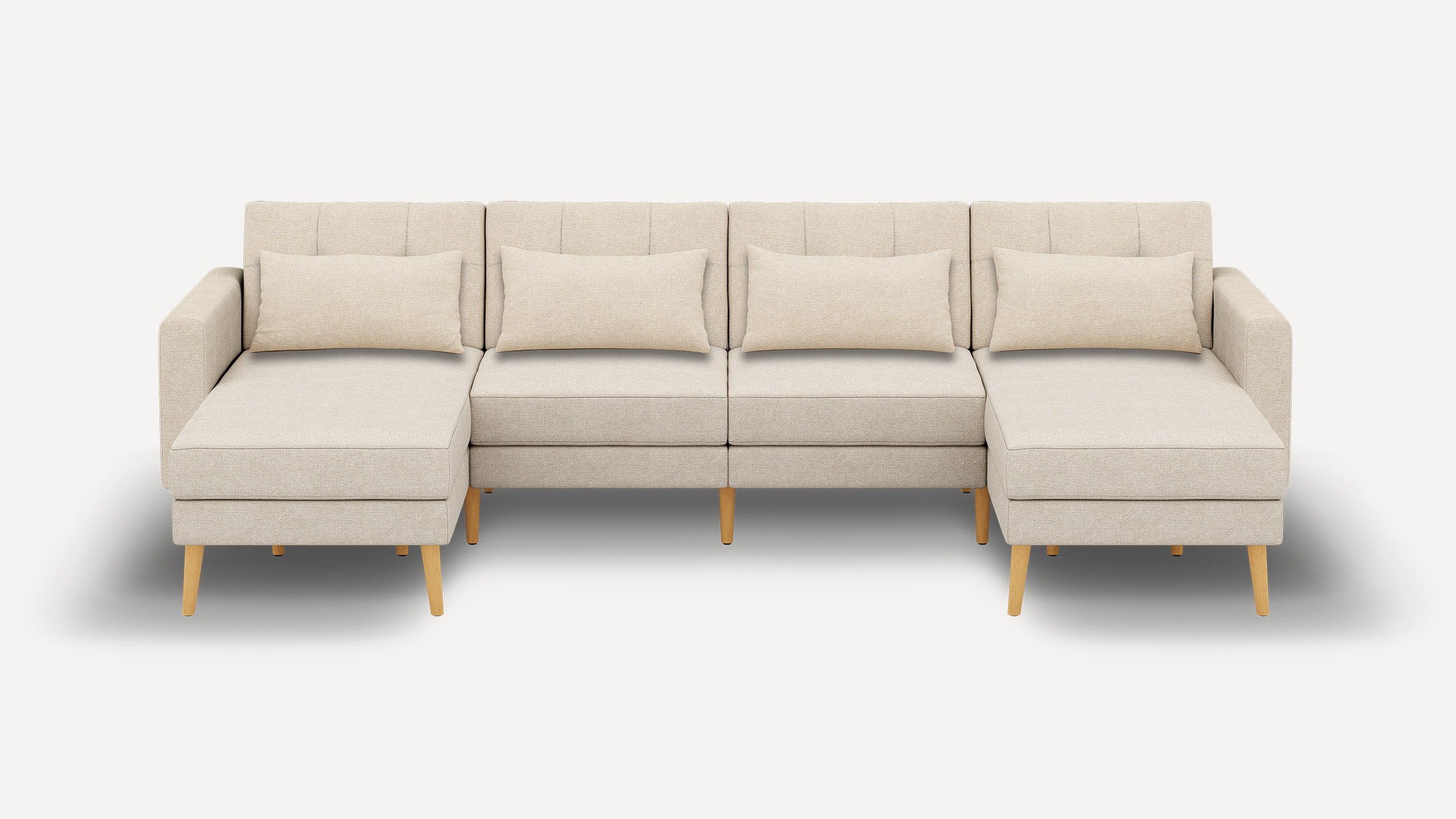 Sectional beige fabric sofa with wooden legs, featuring two chaise lounges and four matching lumbar pillows, set against a plain background.