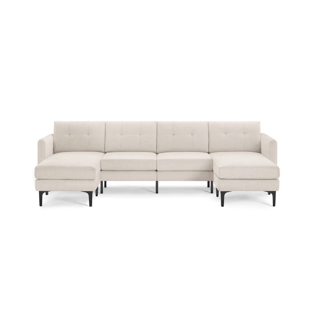 Large modern beige fabric sectional sofa with tufted back cushions and black tapered legs, featuring two chaise lounges on each end.