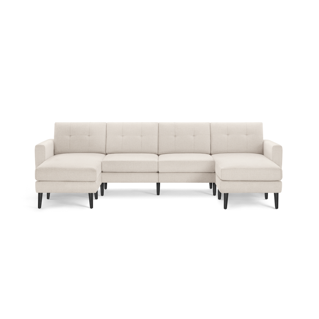 Cream-colored fabric sectional sofa with tufted back cushions, L-shaped design, and black wooden legs.
