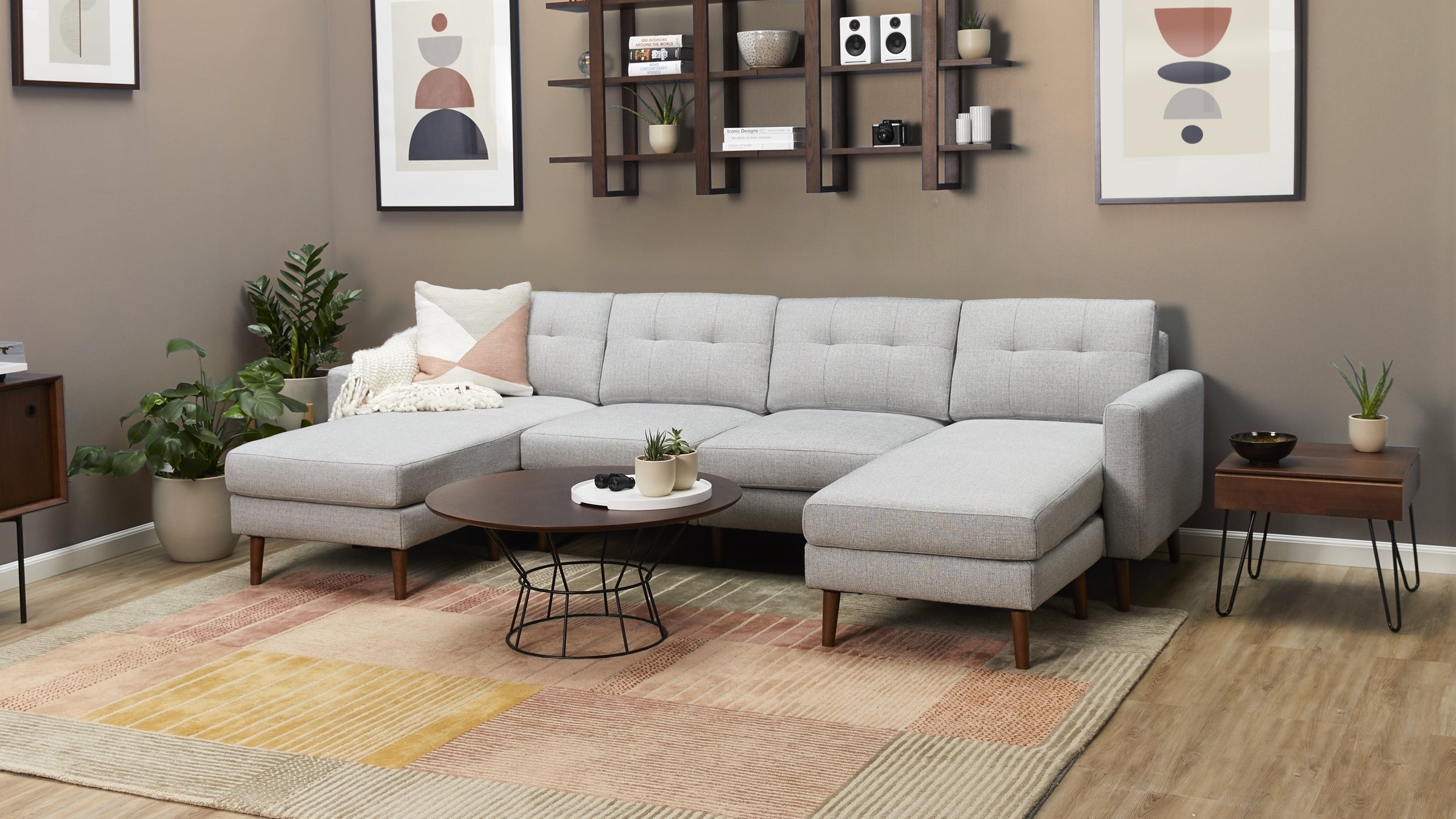 Light gray fabric sectional sofa with tufted cushions, wooden legs, and chaise lounges in a modern living room setting.