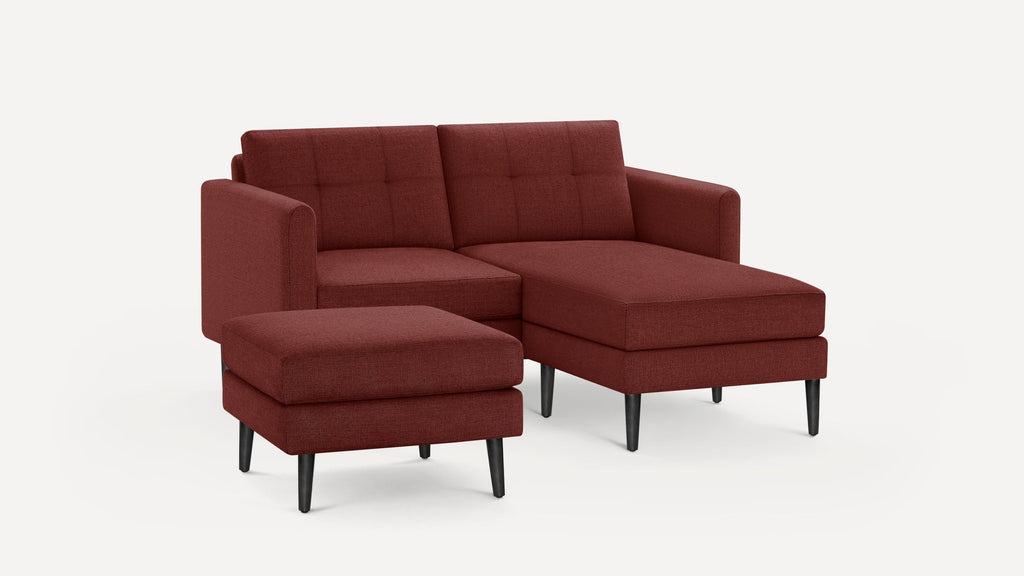 Modern sectional sofa with chaise lounge and matching ottoman, upholstered in deep red fabric with black tapered legs.