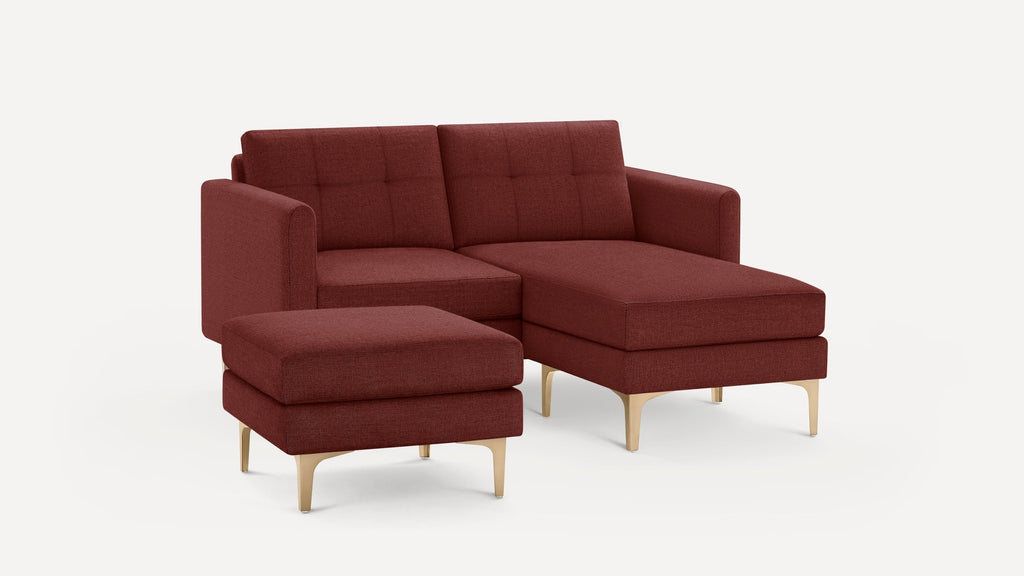 Modern sectional sofa set in dark red fabric with tufted backrests, gold legs, and matching ottoman on a white background.